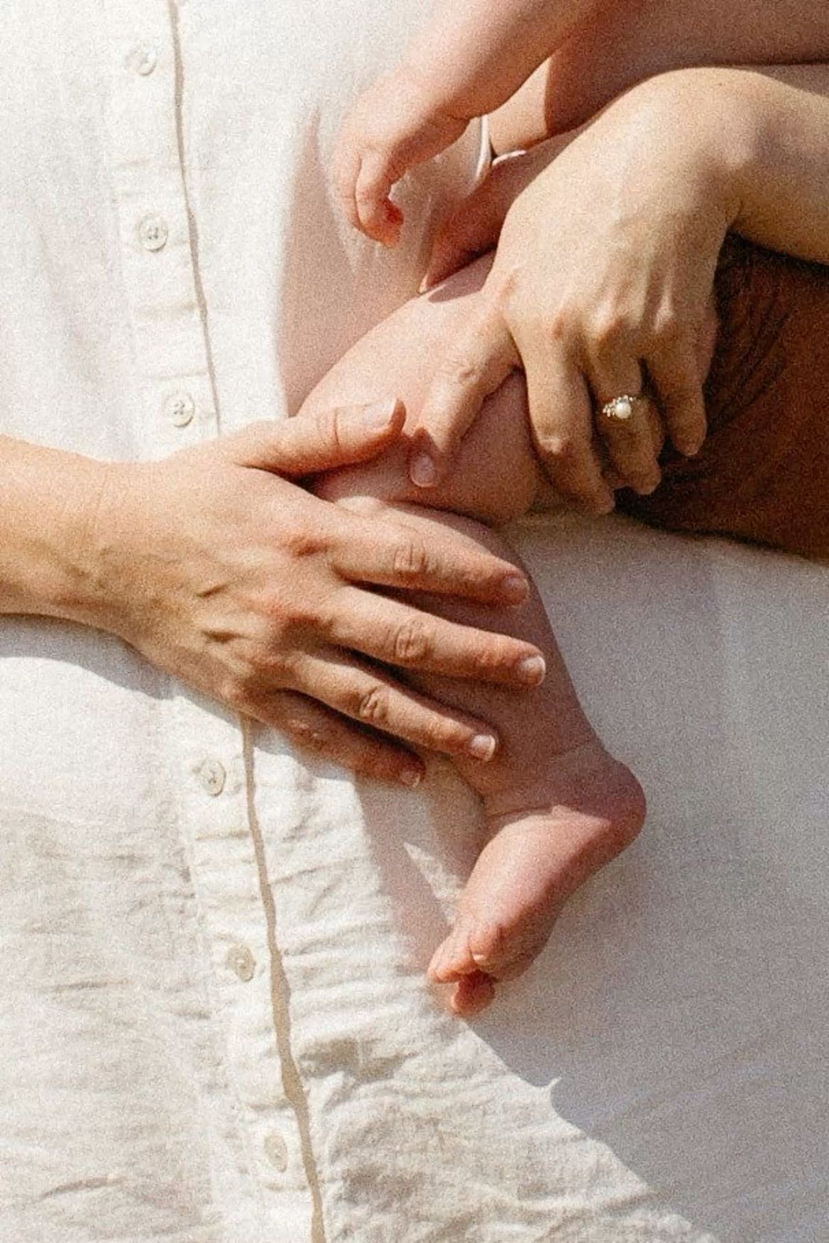 A baby's feet peeking from under a white blanket beside a soft bunny